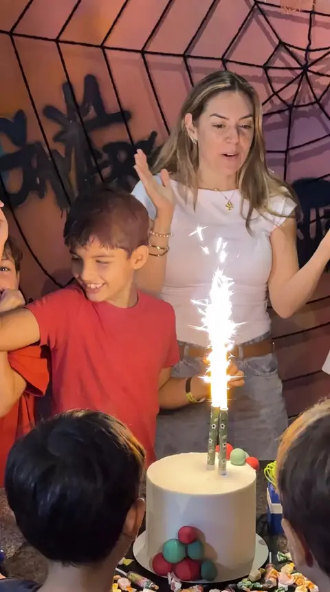 El cumpleañero con la torta y la bengala, y la mamá aplaudiendo
